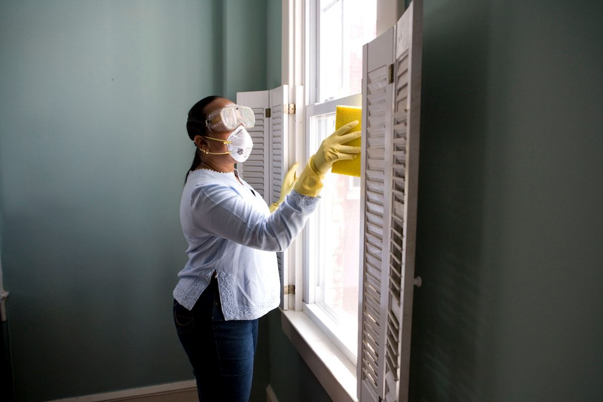Professional cleaner sanitizing a window with commercial supplies